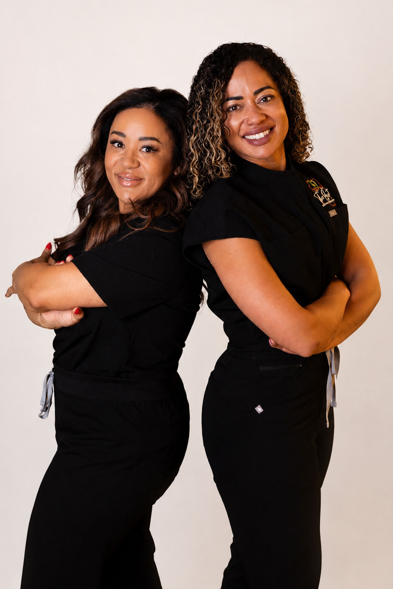 two girls posing standing side by side with arms crossed
